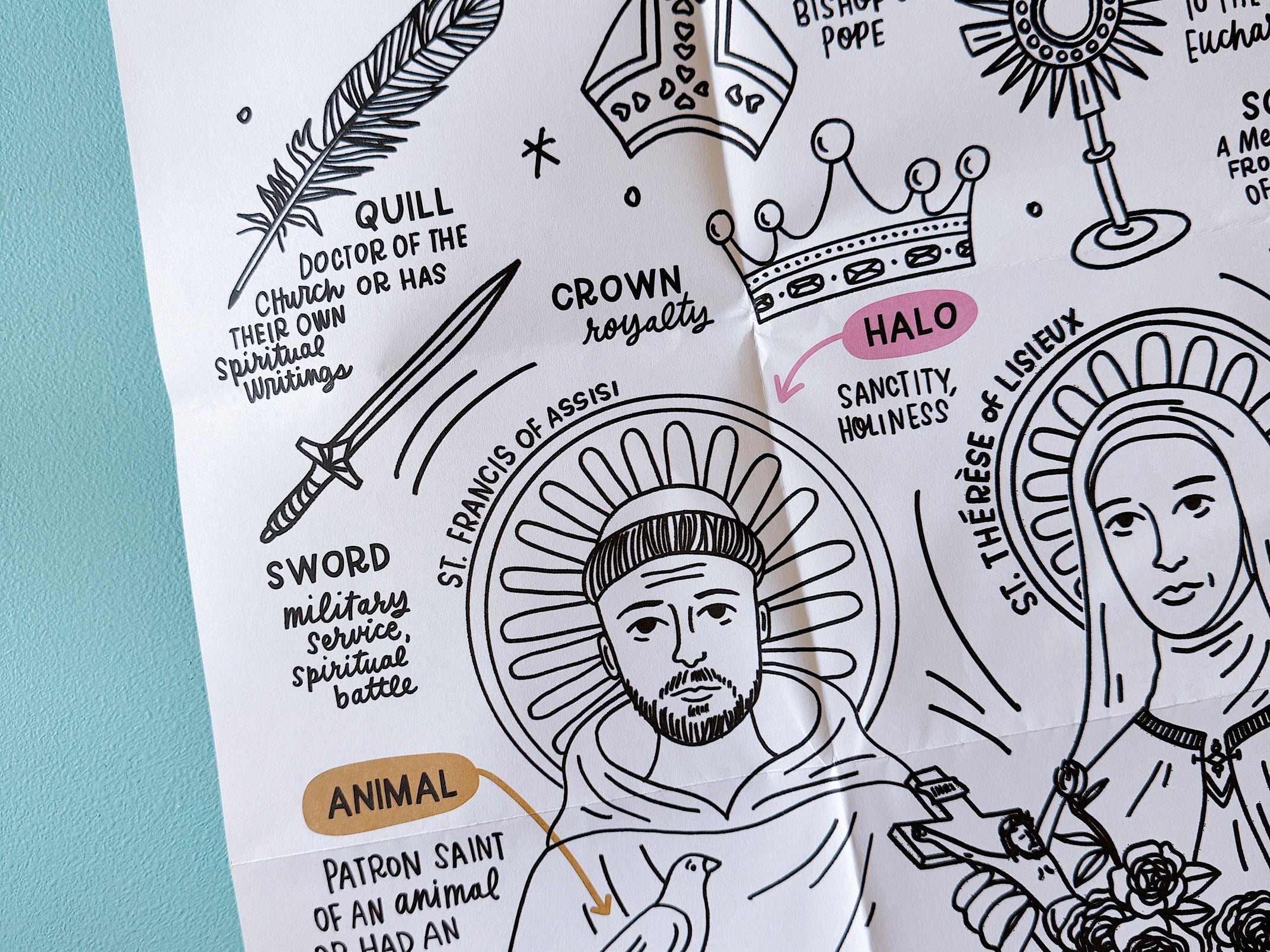 Coloring sheet close-up of St. Francis of Assisi with a bird, labeled with iconography symbols like quill, sword, crown, halo, mitre, and monstrance