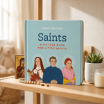 Saints Board Book standing on a shelf with an icon, rosary and candle