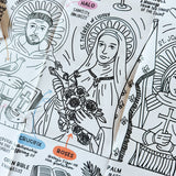Close-up of a folded black-and-white iconography coloring sheet showing saints (St. Francis of Assisi, St. Thérèse of Lisieux) with labeled symbols like halo, crown, crucifix, roses, palm, and open Bible explaining their meanings.