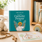 Catholic prayer board book on a shelf with a rosary, lamb plush and Mary statue